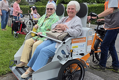Zwei Heimbewohnerinnen sitzen auf einer Fahrradrikscha