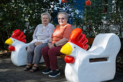 Heimbewohnerinnen sitzend auf Hühnerbank im Park