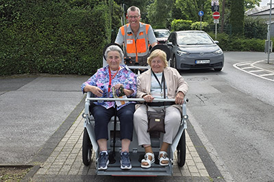 Zwei Heimbewohnerinnen fahren auf einer Fahrradrikscha mit